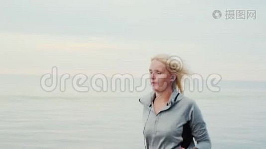 活跃的中年妇女.. 女人在平静的大海或湖泊的背景下慢跑视频