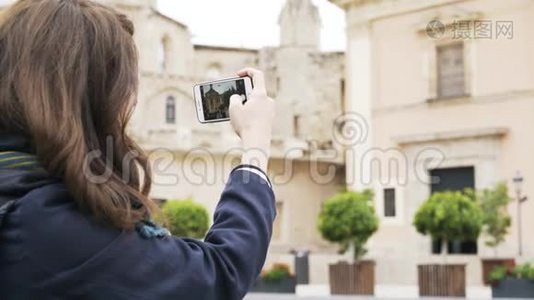 年轻女子正在用手机拍摄巴伦西亚的一栋大楼视频