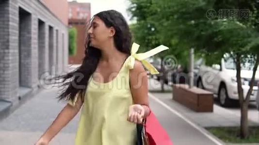 快乐的年轻女孩，黑发，穿着黄色长裙，购物后心情愉快。 慢动作。视频