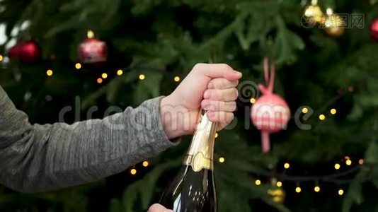 男人双手打开一瓶香槟，装饰圣诞树背景，新年庆祝理念。 男子手视频