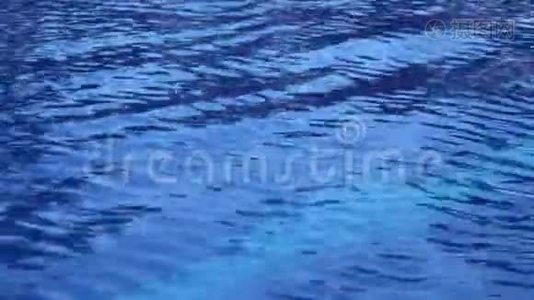 游泳池里的纯蓝色水的波浪表面有光反射。 漂亮的背景视频