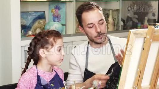可爱的小女孩看着她父亲的艺术家画一幅画视频