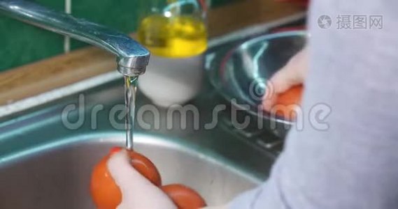 女人`手洗新鲜蔬菜。 洗番茄。视频