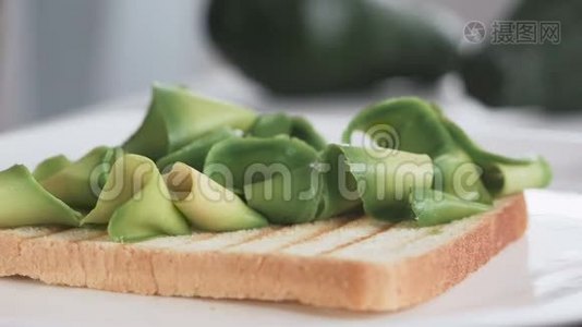 一位妇女正在准备早餐用鳄梨和甜菜根做三明治的手的特写镜头视频