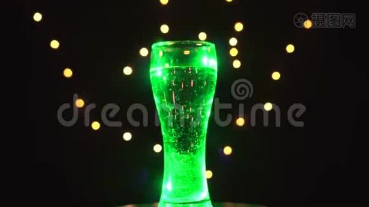 一杯水在五彩的光线下旋转着，鸡尾酒迅速变色.. 酒吧概念视频