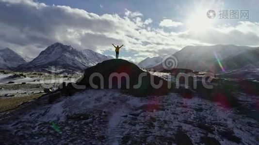 攀登雪峰的男子用冰锥举起双手。 登山者举起双手站在岩石的顶端视频