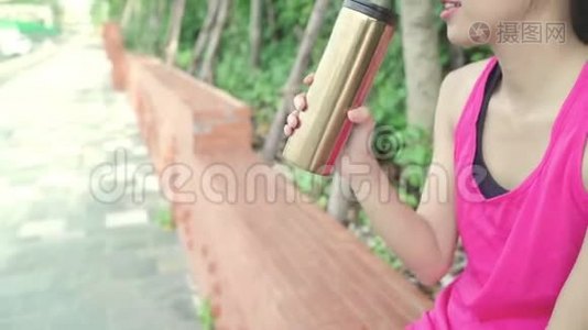 健康美丽的年轻亚洲跑步女子饮水，因为在城市公园街头跑步后感到疲倦。视频