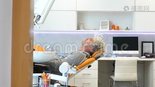 一个正在移动的滑块上的镜头显示一个年轻人坐在牙医椅上，他看着镜头微笑视频