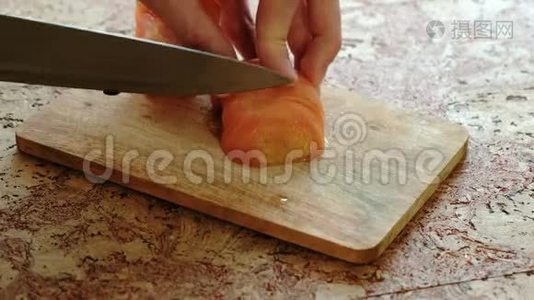 特写男`在厨房桌子上的木板上切西红柿。视频