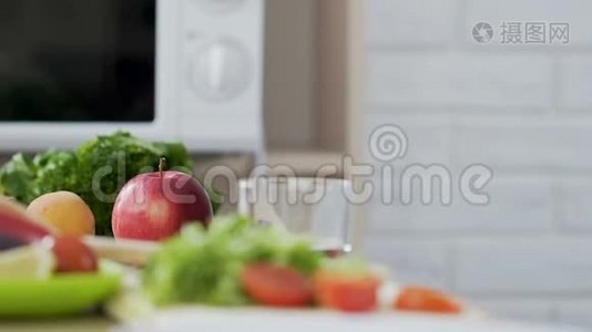 穿绿色连衣裙的女孩从桌子上拿苹果，有机和健康的零食，维生素视频