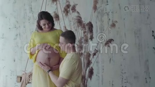幸福的夫妻在家。 丈夫拥抱和抚摸怀孕的妻子的肚子。 慢动作视频