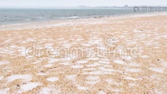 冬天在海沙滩上下雪。 美丽的海景。视频