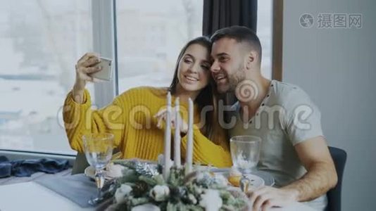 快乐的微笑情侣在室内咖啡厅用智能手机吃午餐和自拍视频