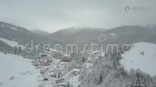 飞越喀尔巴阡山的一个村庄。 鸟`山上白雪覆盖的房子的视野。 乡村景观视频