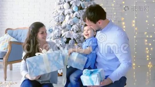 幸福的家庭，爸爸妈妈的儿子，堆着礼物的盒子。 圣诞节背景。视频