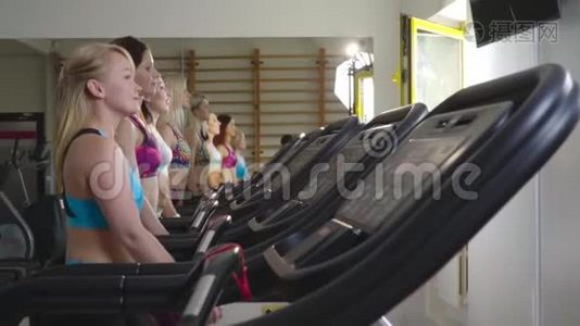 穿着运动服的苗条女性在跑步机上行走，向前看，动作缓慢视频
