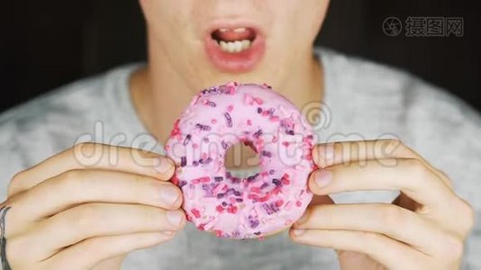 一个饥饿的年轻人吃甜甜圈的肖像视频
