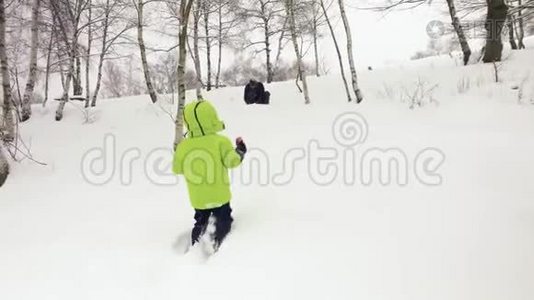 冬天跟着小孩子走到父亲身边，在雪地里玩雪。 家人一起在户外玩视频