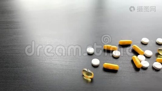 医疗药丸。 黑色桌子上的彩色药丸和胶囊。 药房主题，胶囊丸与药物抗生素在视频