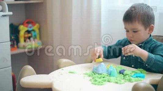 一个小男孩建造城堡和各种形状的绿色动能沙子视频