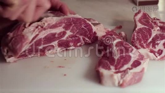 厨师把新鲜猪肉切成牛排。视频