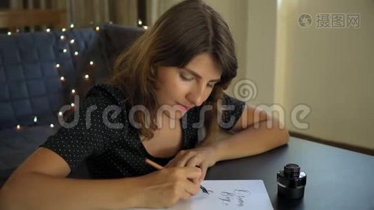 一位年轻女子用刻字技巧在纸上书写书法的特写镜头。 她写着梦想远大的目标视频