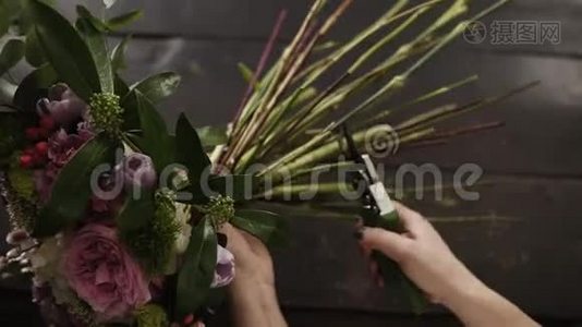美丽的雌性手在黑暗的表面上用子切割花茎。 花卉工作室。 顶级射击视频