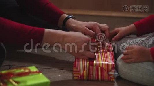 特写女人和女孩的手，用盒子包装礼物，以圣诞节和新年的颜色。视频