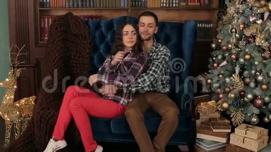 一对夫妇拥抱在圣诞树附近的沙发上。视频