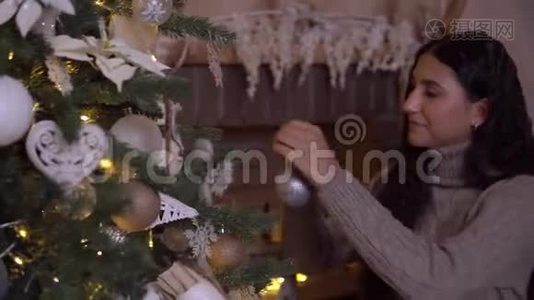 一个女孩装饰一棵圣诞树，一个漂亮的球心情很好。视频