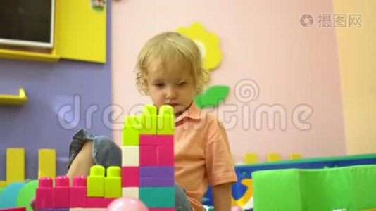 金发学龄前幼儿在幼儿园玩多种颜色的积木。 儿童发展视频