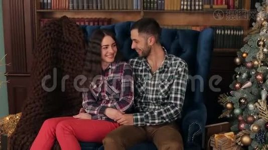 一对夫妇拥抱在圣诞树附近的沙发上。视频