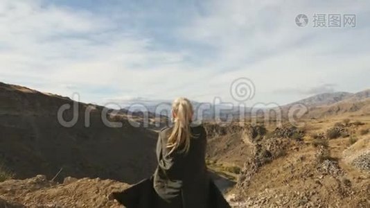 年轻女子站在悬崖边，举起双手，迎着高高的岩石山，在那里晒太阳视频