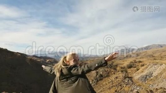 年轻女子站在悬崖边，举起双手，迎着高高的岩石山，在那里晒太阳视频