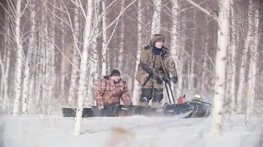 两个人骑着一辆带拖车和机动的迷你雪车穿过冬林视频