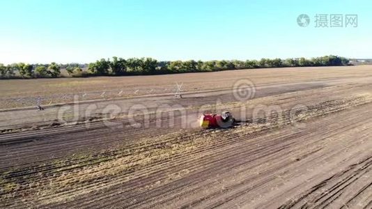 空中录像。 农业机械在农业领域收获新鲜的有机马铃薯。 加上拖拉机，红色视频
