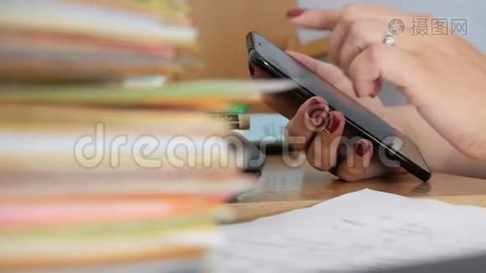 女性手在桌面上使用智能手机，上面有文件和文件视频