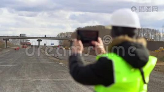 工程师以道路施工为背景，看了看碑上的施工方案。视频