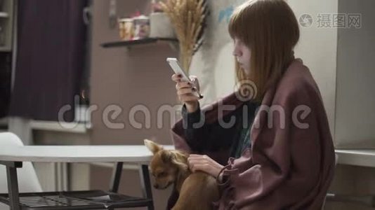 年轻漂亮的红发女人晚上在厨房用智能手机视频