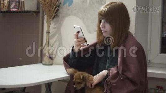 年轻漂亮的红发女人晚上在厨房用智能手机视频