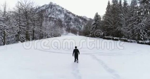 空中向前飞人，穿着雪鞋走在山上，白雪覆盖的田野，在寒冷的冬天，松林森林附近视频