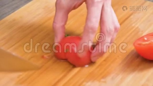女性手拿刀的特写是在木切割板上切西红柿做沙拉。 家庭厨房视频