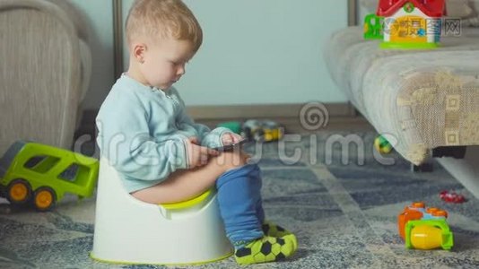 可爱的男孩带着智能手机在房间里的厕所训练。视频