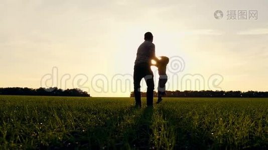 日落时分，快乐的父子在公园里玩大自然。 父亲牵着他的儿子的手，和他一起转身。 慢慢视频