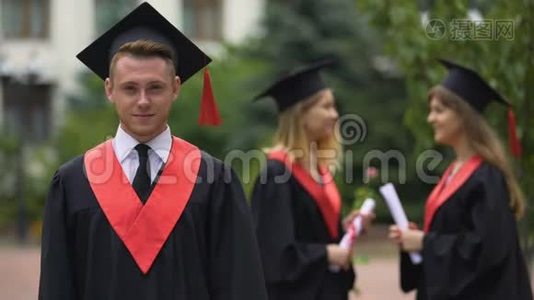 毕业典礼，穿着学术服装的快乐男人看着镜头，笑着视频