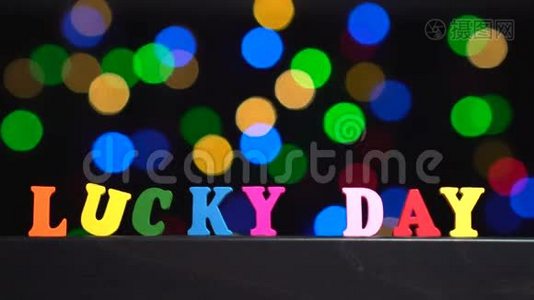 彩色的文字`幸运的一天`从多种颜色的木制字母前面抽象模糊的灯光，背景视频