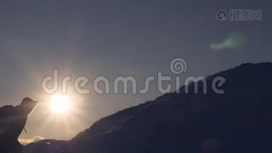 游客在美丽的天空的背景下爬到山顶。 登山者在明亮的阳光下爬上雪山。 男人视频