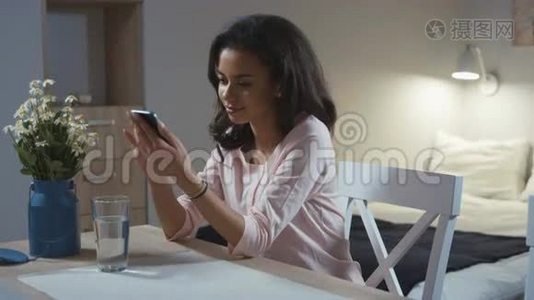 年轻的女人在家里用手机。视频