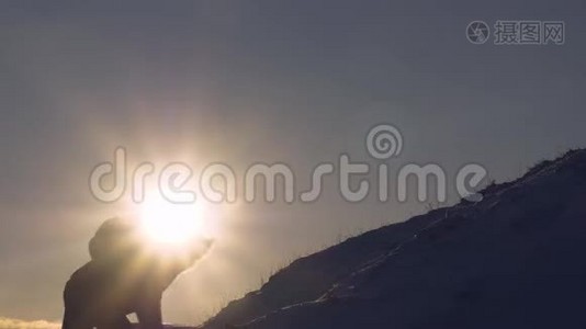 登山者在明亮的阳光下爬上雪山。 游客在美丽的天空的背景下爬到山顶。 男人视频