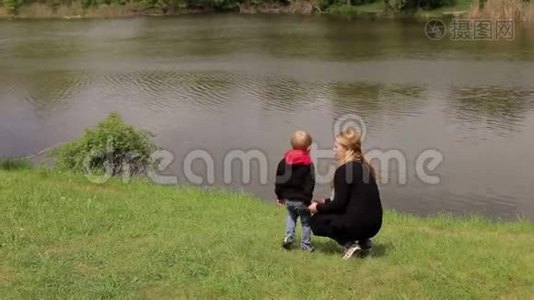 妈妈和儿子坐在河岸上的草地上视频